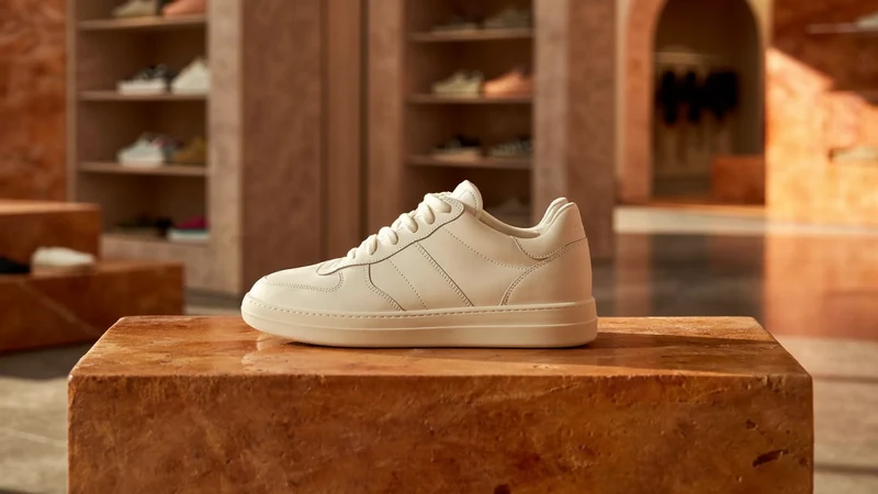 Et par råhvide læder-sneakers på en rå lersokkel i blødt lys