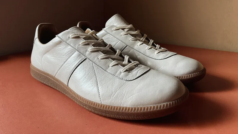 Low-top læder-sneakers med karamelfarvet gummisål på en varm terrakottaflade